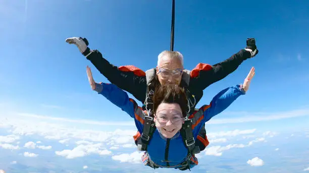 A woman is enjoying her first parachute jump. She jumped with an experienced skydiving instructor.