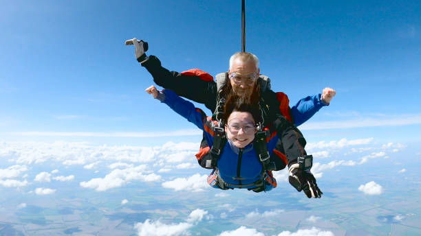 Happy woman enjoy free fall with experienced parachuting instructor. A woman is enjoying her first parachute jump. She jumped with an experienced skydiving instructor. skydiving stock pictures, royalty-free photos & images
