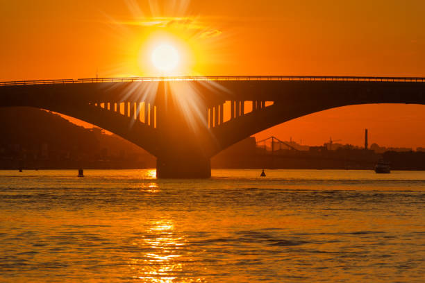 istock Silhouette of bridge across river and setting sun over it 1251269284