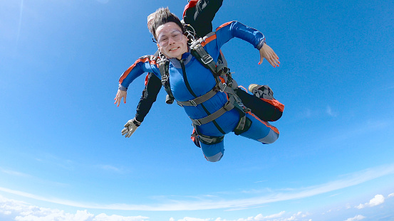 A woman is enjoying her first parachute jump.  She jumped with an experienced skydiving instructor.