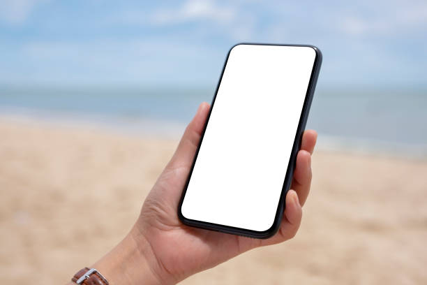 istock hands holding black mobile phone with blank desktop screen by the sea 1251269477