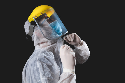 Medical doctor, nurse, surgeon, psychologist working with protective mask, glasses and gloves helping people in the days of panic, pandemic - studio shot on black background.