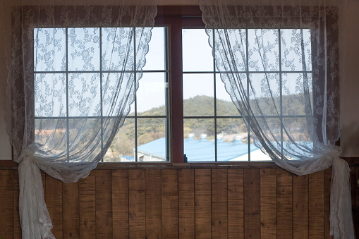 Old wooden window with white lace curtains