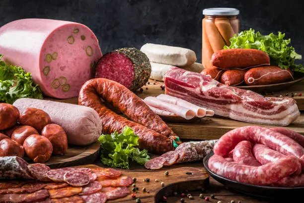 Photo of Various kinds of raw sausages on a rustic wooden table