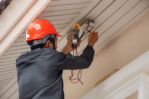 Electrician man hand holding clamp  multi meter and checking voltage at the electrical terminal, change LED lamp at home.Maintenance concept.