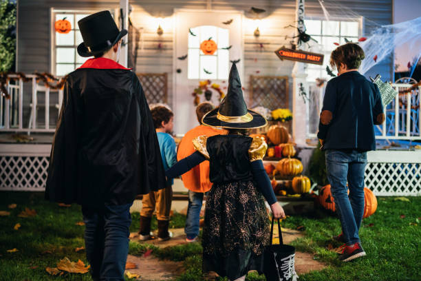 Young kids trick or treating at night during Halloween stock photo