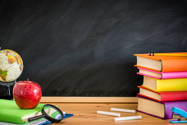 黒板の背景ホイットコピースペースに対する本でいっぱいの教師デスク - back to school blackboard education apple ストックフォトと画像