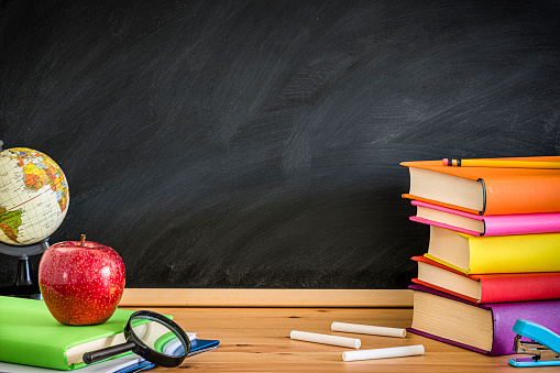 Back to school concept. Asian female teacher smiling with wooden stick pointing to blackboard at school in classroom, Happy beautiful young woman standing hold pointer to back board