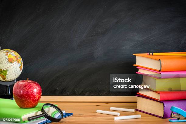 Teacher Desk Full Of Books Against A Blackboard Background Whit Copy Space Stock Photo - Download Image Now