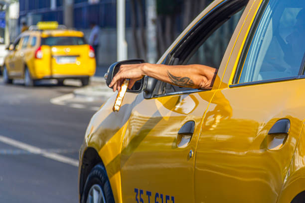 A taxi driver is putting his arm out of the window Konak, Izmir,Turkey – June 20, 2020: A taxi driver is watching traffic lights and waiting to move, meanwhile he is holding a pastry food with putting his arm out of the taxi's window at Fahrettin Altay Street, in Konak, in Izmir. turkey tattoo stock pictures, royalty-free photos & images