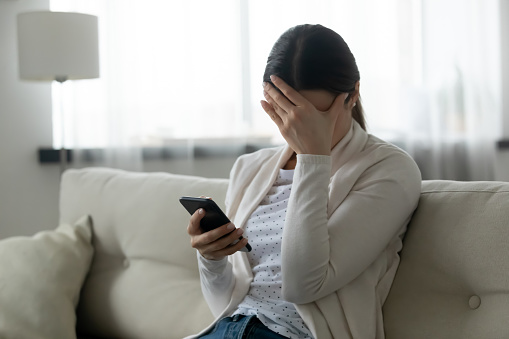 Mujer estresada sosteniendo teléfono inteligente se siente humillado, concepto de ciberacoso photo