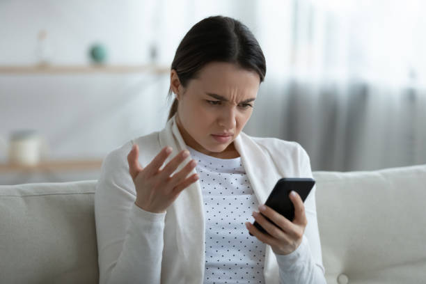 раздраженная женщина, держащая смартфон, имеющих проблемы с гаджетом чувствует раздражение - watch battery стоковые фото и изображения