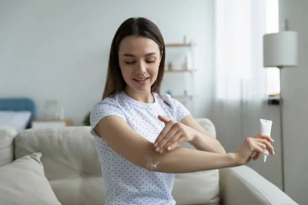 Photo of Woman creme holding tube apply cream nourish elbow area