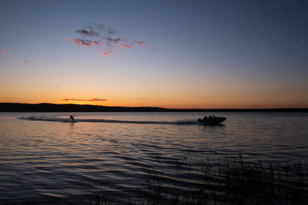 istock on a board behind a boat on a lake against the setting sun 1251274153