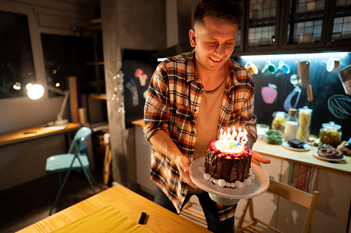 Young Caucasian man holding a birthday cake for someone special.
