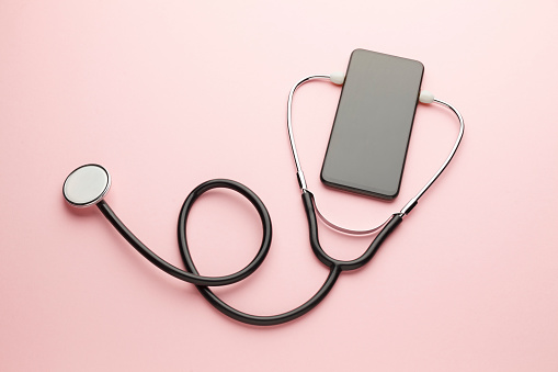Smartphone and stethoscope on pink background. Online medicine (telemedicine) technology. Service for remote diagnostic, chat with doctor.