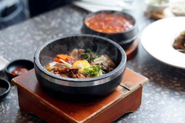 istock Dolsot bibimbap - Korean mixed rice, Include steamed rice, vegetables, pork and fried egg on top, served in a hot stone pot. 1251277189