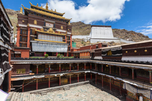 Front view of Tashi Lhunpo (Tashilhunpo) Monastery  in courtyard on summer sunny day with blue sky and cloud, Thanka wall in background, Shigatse, Tibet, China Front view of Tashi Lhunpo (Tashilhunpo) Monastery  in courtyard on summer sunny day with blue sky and cloud, Thanka wall in background, Shigatse, Tibet, China dalai lama stock pictures, royalty-free photos & images