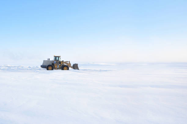 Grader clears snow on ice road on Lena river after storm