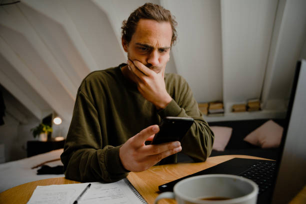 istock Young creative male working from home, receiving text message, confused and unsure 1251284337