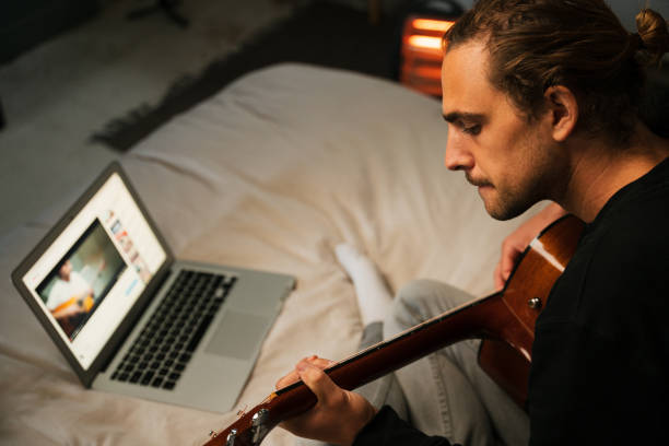 istock Young caucasian male learning guitar online with laptop 1251284544