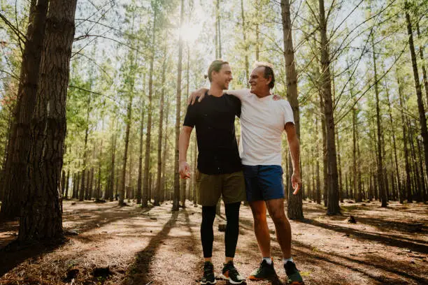 Photo of Caucasian father and son embracing after a run together in the woods