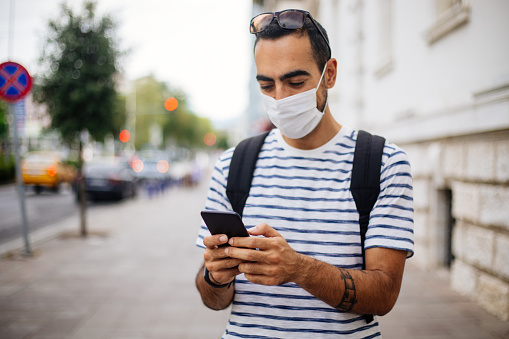 Portrait Of Man Using Phone With Mask On The Street