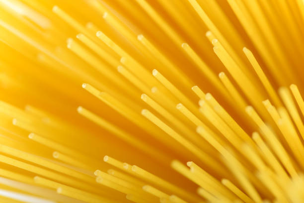 Long yellow spaghetti pasta food ingredient. Uncooked dry macaroni. Thin raw noodle. Cereal wheat product for delicious gourmet cooking. A useful source of carbohydrates. Healthy italian pasta.