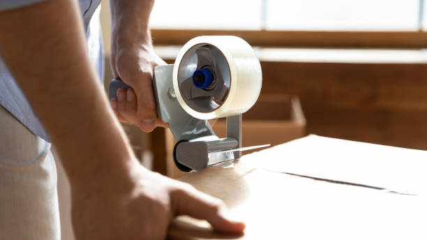 istock Close up man using adhesive tape dispenser, packing box 1251287008
