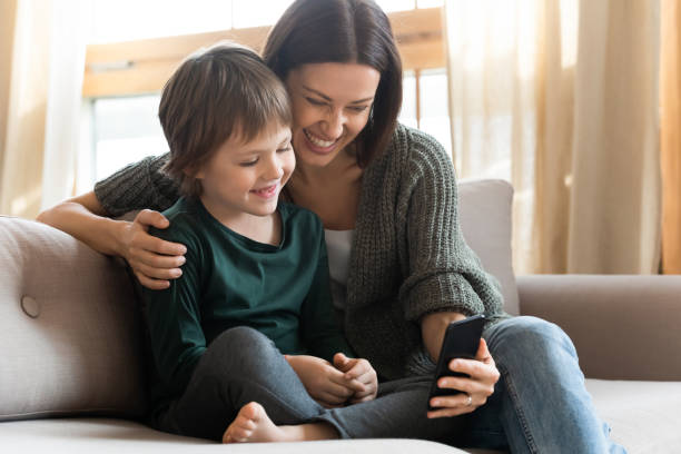 istock Happy mother and little son using smartphone together, sitting on sofa 1251287079