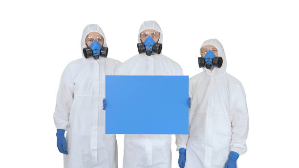 istock Three doctors in protective suits holding blank board on white background 1251288826