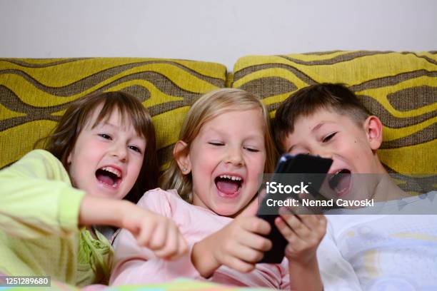 Kids Laugh As They Watch A Funny Video Over A Smartphone In The Morning  Stock Photo - Download Image Now - iStock