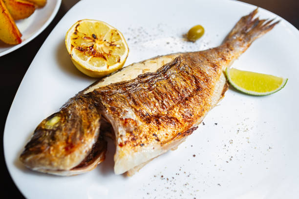 Delicious dorado fish cooked on grill with lemon,lime in Asian seafood restaurant.Gourmet mahi-mahi grilled for dinner in Asian sea food cafe.Healthy natural cuisine in Asia