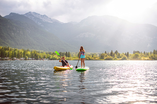 Mid adult man and woman paddleboarding and kayaking side by side while vacationing in Triglav National Park.