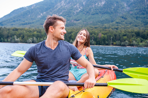 Mid adult Caucasian couple smiling as they rest from paddling their tandem kayak while vacationing in Triglav National Park, Slovenia.