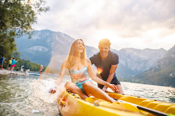 carefree mid adult couple preparing to kayak on lake bohinj - sport exercising men julian alps imagens e fotografias de stock