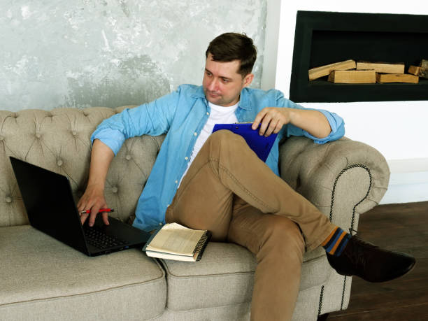 istock Remote work. A young guy works at home with a laptop and documents. 1251300497
