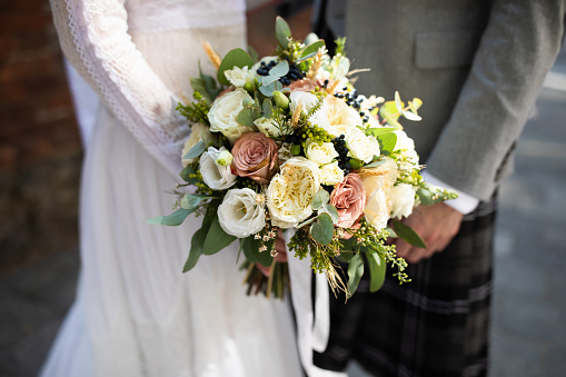 Couple holding a wedding bouquet. Natural light.