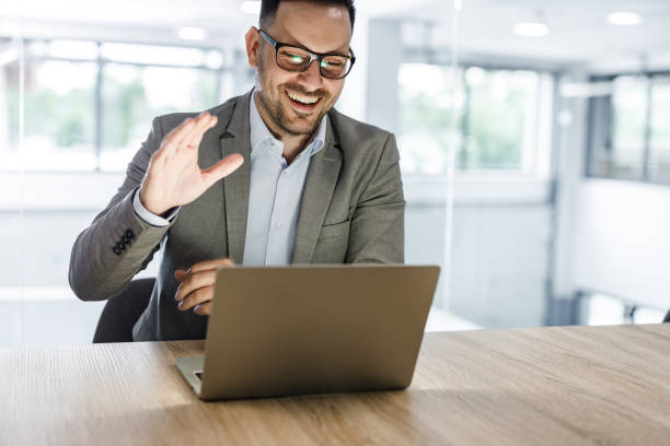 istock Happy entrepreneur waving while having a conference call over laptop in the office. 1251300998
