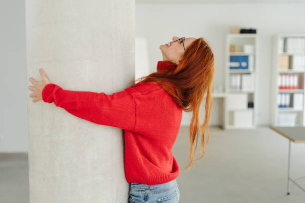 istock Exuberant young woman hugging an indoor pillar 1251303969