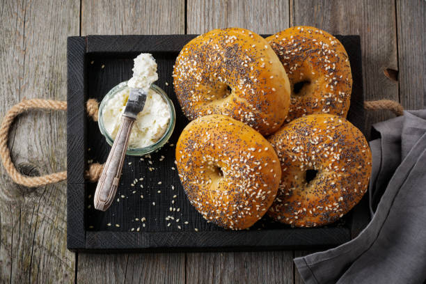 istock Bagels in wooden rustic box  with  textile napkin on  old wooden background. Selective focus. Top view. Copy space. 1251304607