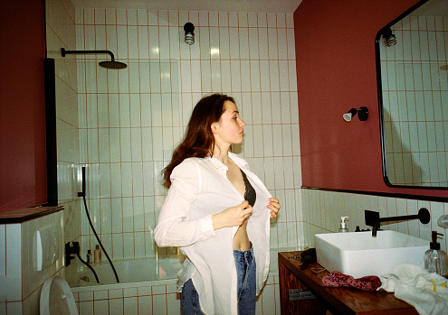 Young Caucasian woman getting dressed in bathroom
