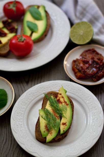istock Bruschetta style rye bread toasts with avocado, sun-dried tomatoes, basil, dill and lime. Rustic dark wooden background 1251305633