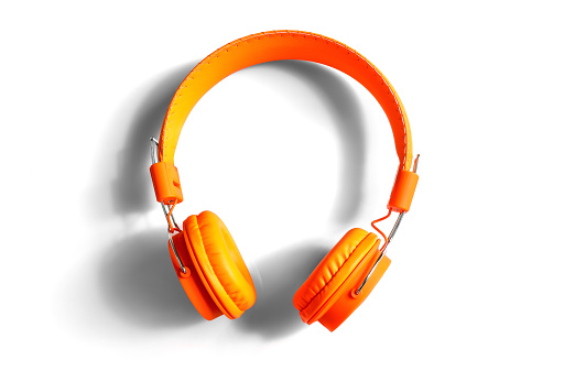 Modern orange studio headphones isolated on white background.