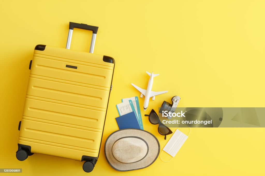Medizinische Maske, Koffer mit Sonnenhut, Kamera, Reisepass, Flugzeugticket, Sonnenbrille und Flugzeug auf gelbem Hintergrund - Lizenzfrei Reise Stock-Foto