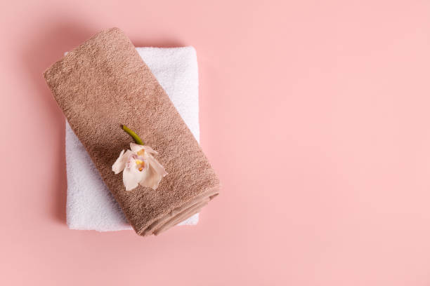 istock Bath towels and white orchid flower on pink background 1251308846