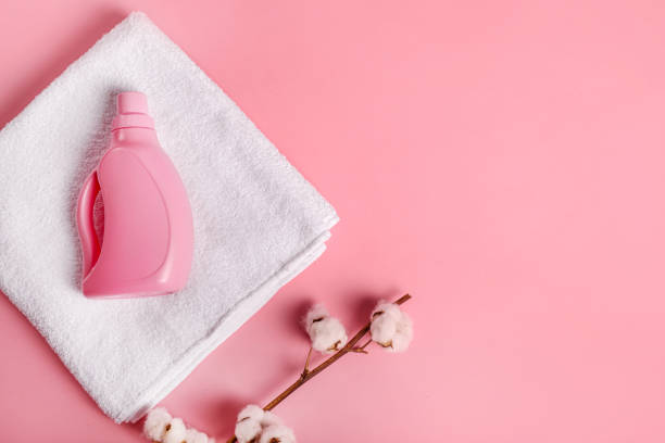 istock White bath towel, detergent and cotton branch on pink background 1251308925