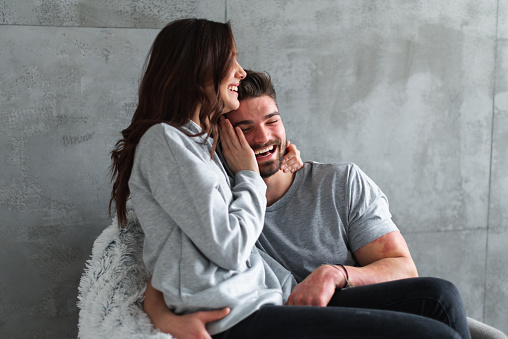 Young couple is so happy about moving in to their new apartment. They are hugged on the floor.