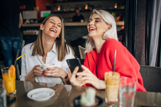 istock Two young ladies sitting in cafe and using smart phone 1251309110