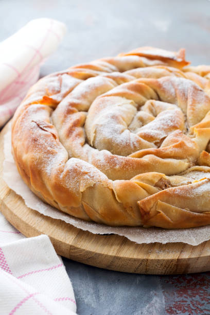 istock Round burek pie with an apple on a dark background. Traditional Serbian cuisine. Selective focus. Top view. 1251309329